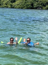 A cheerful couple enjoys a refreshing swim in clear waters, showcasing the fun and relaxation of a perfect day on the water.