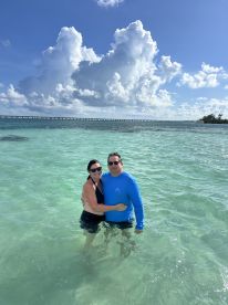 A couple enjoys a romantic moment while wading in the clear waters, surrounded by stunning scenery — perfect for beach getaways and memorable experiences.