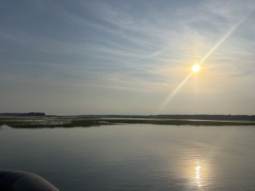 A serene sunset view over calm waters, showcasing the beauty of nature and the tranquility of a boating experience.