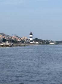A distant view of a lighthouse along a waterfront, surrounded by residential buildings. The image lacks clarity and detail.