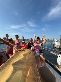 A joyful family poses on the deck of a boat, waving and enjoying their time together — perfect for capturing memorable moments on the water.