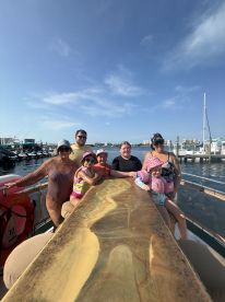A joyful family poses together on a boat, showcasing a fun day out on the water with smiles all around.