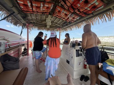 Guests enjoy a lively atmosphere inside the boat's cabin, complete with seating and a helm, perfect for socializing and relaxation while on the water.