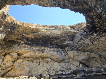A stunning view of a natural cave formation with a clear blue sky above, showcasing the beauty of coastal landscapes — perfect for adventure seekers exploring hidden gems.