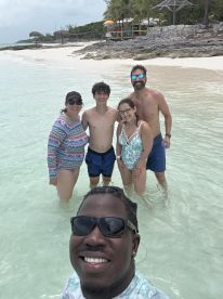 A joyful group of friends and family enjoy a fun day at the beach, wading in the shallow waters — a perfect moment for creating lasting memories in paradise.