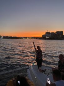 A lively group enjoys a stunning sunset aboard a catamaran, capturing the perfect moment of celebration on the water.