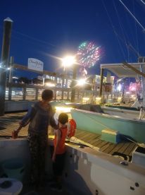 A family enjoys a fireworks display from the deck of their boat, creating a memorable night of celebration by the water.