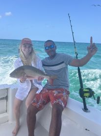 A couple proudly displays their catch while fishing on a boat, capturing the excitement of a successful day on the water.