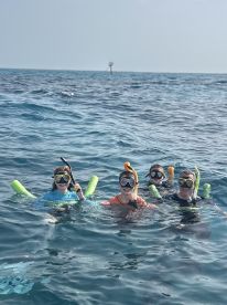 A joyful group of children enjoys snorkeling in clear waters, showcasing a fun family adventure in the ocean.