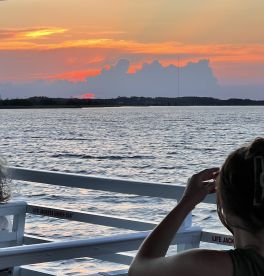 A serene sunset view from a boat, with a guest enjoying the picturesque scenery — perfect for romantic evenings or peaceful cruises.