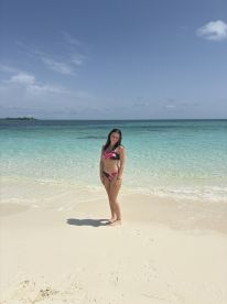 A young woman stands on a pristine beach with turquoise waters, capturing the essence of a perfect tropical getaway.
