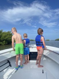 Three children in life jackets enjoy a scenic boat ride, gazing at the beautiful surroundings — a perfect adventure for young explorers.