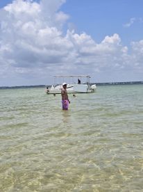 A fun day at the beach with a group enjoying the water, while a boat is anchored nearby — perfect for summer outings and family adventures.