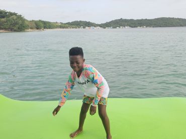 A joyful child enjoys playing on a vibrant floating mat in the water, showcasing the fun and excitement of water activities during a boat trip.