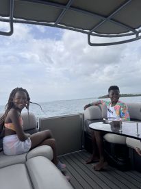 Two children enjoy a fun day on a pontoon boat, smiling and relaxing as they take in the beautiful water views — perfect for family outings.