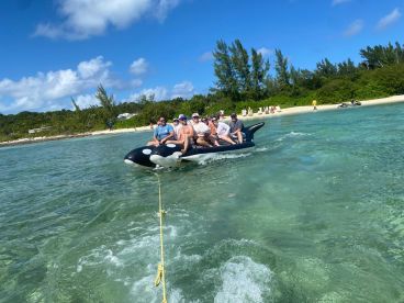A group of friends enjoys a thrilling ride on a banana boat in clear waters, perfect for summer adventures and beach fun.