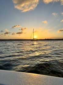 A serene sunset view featuring a sailboat silhouetted against the vibrant sky, perfect for capturing the beauty of evening cruises on the water.