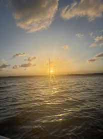 A stunning sunset view featuring a sailboat silhouetted against the vibrant sky, perfect for capturing the essence of tranquil evenings on the water.