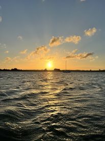 A stunning sunset over the water, with gentle waves reflecting the golden light, creating a serene backdrop for any boating adventure.