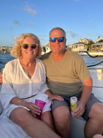 A couple enjoys drinks on a boat during sunset, capturing a perfect moment of relaxation and celebration on the water.
