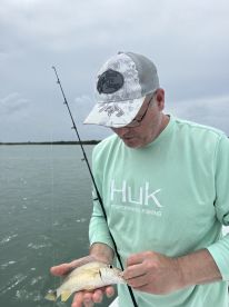 A man proudly holds up his catch while fishing on a boat, showcasing the thrill of the sport and the joy of a successful day on the water.