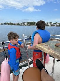 Two children wearing life jackets enjoy a day on the water, taking in the scenic views from the boat — a perfect family outing.