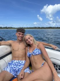 A cheerful couple enjoys a sunny day on a boat, showcasing the perfect summer vibe for fun and relaxation on the water.
