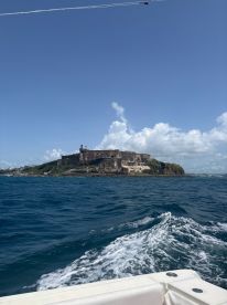 A picturesque view of a historic fortress from the water, showcasing the stunning coastline and vibrant blue skies — a perfect backdrop for a boating adventure.
