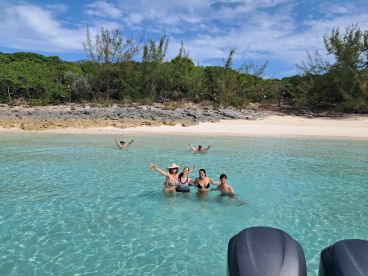A joyful group enjoys a refreshing swim in the crystal-clear waters of a secluded beach, perfect for family outings and fun in the sun.