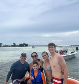 A joyful family poses together on a boat, enjoying a fun day at the beach — perfect for creating lasting memories on the water.