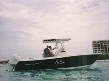 A couple poses happily aboard the Pro-Line boat named 'Sea Anne' in tranquil waters, capturing a joyful moment on their boating adventure.