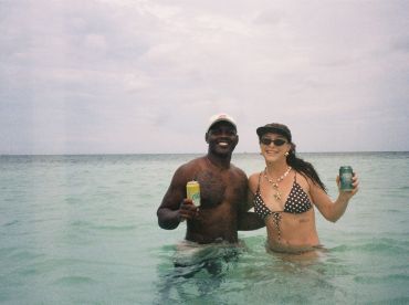 A joyful couple enjoys a refreshing drink while wading in the clear waters, capturing the essence of a fun day at the beach.