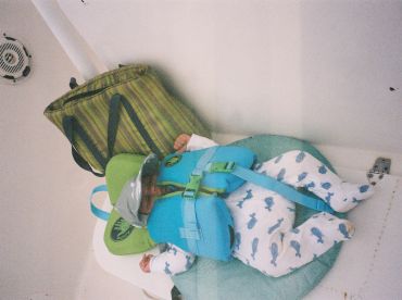 A baby comfortably resting in a life jacket inside a boat cabin, showcasing safety and relaxation on the water.