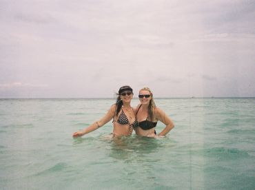 Two friends enjoy a refreshing swim in clear turquoise waters, capturing a fun beach moment perfect for summer adventures.