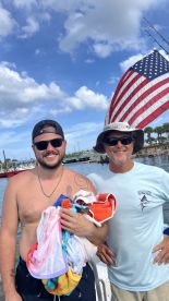 Two friends pose with towels on a boat, enjoying a sunny day on the water — perfect for summer adventures and memorable outings.