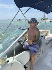 A cheerful captain enjoys a sunny day on the water, showcasing the fun and excitement of boating adventures.
