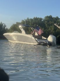 A boat with an American flag is anchored in serene waters surrounded by mangroves, showcasing a perfect day on the water.