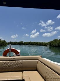 A cozy interior view of a Sea Ray boat, showcasing comfortable seating and a scenic waterway in the background — perfect for relaxing on a sunny day.
