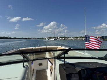 A scenic view from the helm of a boat, showcasing the calm waters and a distant marina under a clear blue sky — perfect for a day of cruising.
