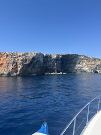 A stunning view of a rugged coastline from a boat, showcasing the vibrant blue waters and dramatic cliffs — perfect for scenic boat tours.