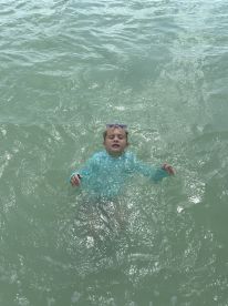 A child enjoys swimming in clear waters, showcasing a fun day at the beach. Perfect for family-friendly aquatic adventures.