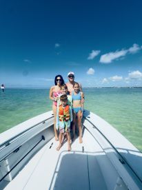 A joyful family poses on the bow of a boat, enjoying a sunny day on the water — perfect for family outings and aquatic adventures.