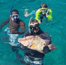 A group of snorkelers showcases a large fish while enjoying an underwater adventure — a thrilling experience for marine life enthusiasts.