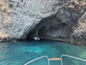 A boat navigates into a stunning cave along the coastline, showcasing the beautiful turquoise waters and rocky formations — a perfect adventure for exploring hidden gems.