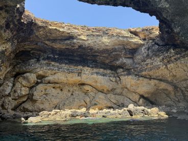 A stunning view of a natural cave with swimmers enjoying the clear waters, showcasing the beauty of coastal adventures and exploration.