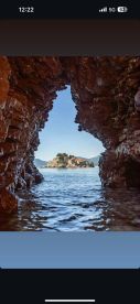 A stunning view of an island framed by rocky formations, showcasing the beauty of coastal landscapes — perfect for exploring hidden gems by boat.