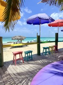 A vibrant beach scene featuring colorful umbrellas and seating, perfect for relaxing by the water. Ideal for beachgoers looking for a sunny getaway.