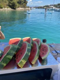 Fresh watermelon slices are displayed on a boat, perfect for enjoying a refreshing snack while paddleboarding in crystal-clear waters.
