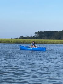 Two individuals enjoy a peaceful kayaking experience in calm waters, surrounded by lush greenery — a perfect way to explore nature.