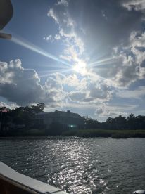 A stunning view of sunlight breaking through clouds over tranquil waters, capturing the serene beauty of a boating experience.